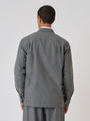 Back view of a model wearing the Charcoal Organic Chambray Lucky Shirt. The shirt is a relaxed fit and made of a textured charcoal fabric. Simple white studio background.