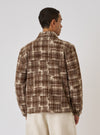 Back view of a model wearing the Sand Patch Check Fleece Rams Jacket. The brown and cream jacket is styled in front of a plain white background.