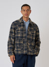 A man poses in front of a white background wearing the Navy Patch Check Fleece Rams Jacket. The jacket is a blue and tan plaid.