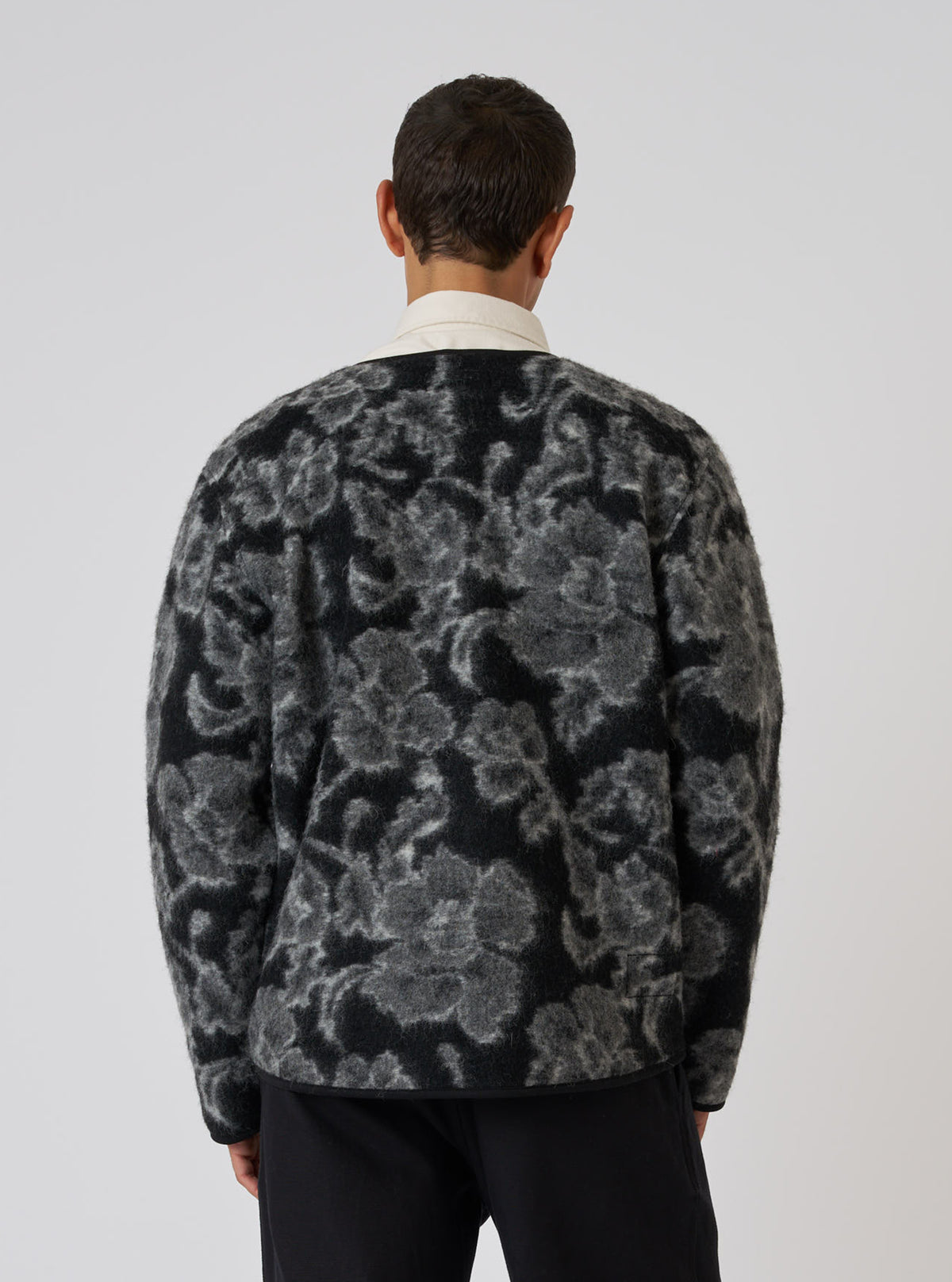 Back view of a model wearing a Charcoal Flower Fleece Zip Liner Jacket. The jacket has a black and gray floral pattern. Shot against a white background.