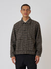 A model poses in a Brown Jacquard Knit Rams Jacket against a white backdrop. The jacket features a brown and beige pattern, button closure, and a relaxed fit.