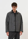 A model is wearing the Grey/Blue Jacquard Weave Field Jacket against a plain white background. The jacket features a complex textured pattern in shades of grey and blue, a classic pointed collar, a button-down front, and several large utility patch pockets. The model is shown from the waist up, highlighting the garment's relaxed fit and structured design. No mannequin is present in the image.