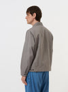 The Mid Grey Linen Slub Weave E130 Jacket is displayed flat against a plain white background. The image shows the back of the jacket, highlighting the two adjustable button tabs at the waist, reinforced elbow patches on the sleeves, and a straight hem.