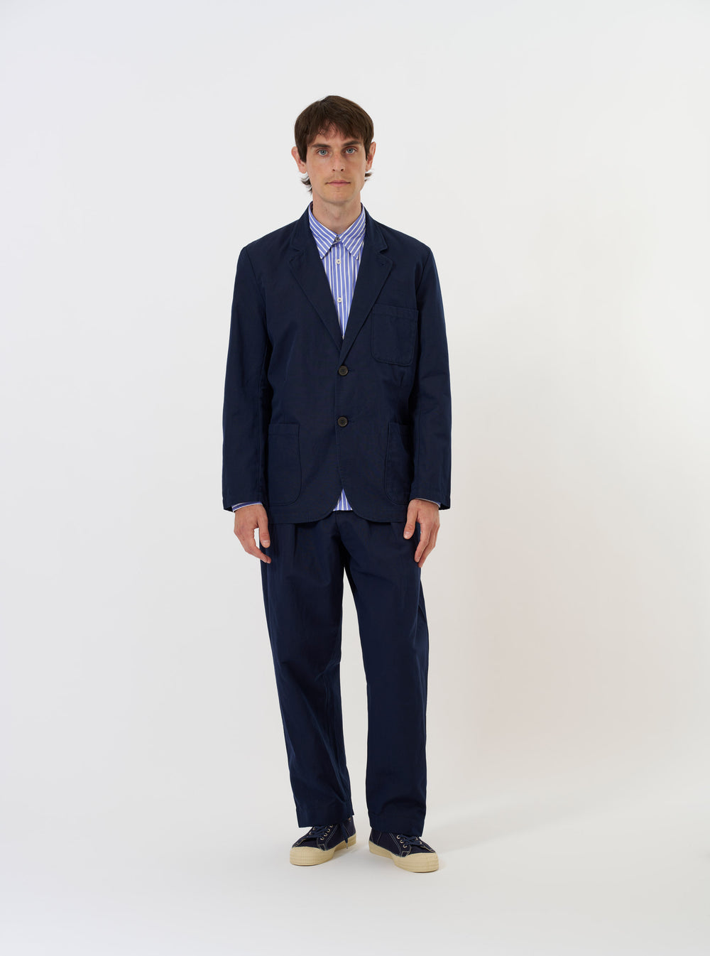 A Navy Linen Slub Weave Two Button Jacket is shown laid flat against a plain white background. The jacket features a classic notch lapel, a two-button front fastening, and three patch pockets on the front. The textured slub weave of the navy blue linen-cotton fabric is visible.