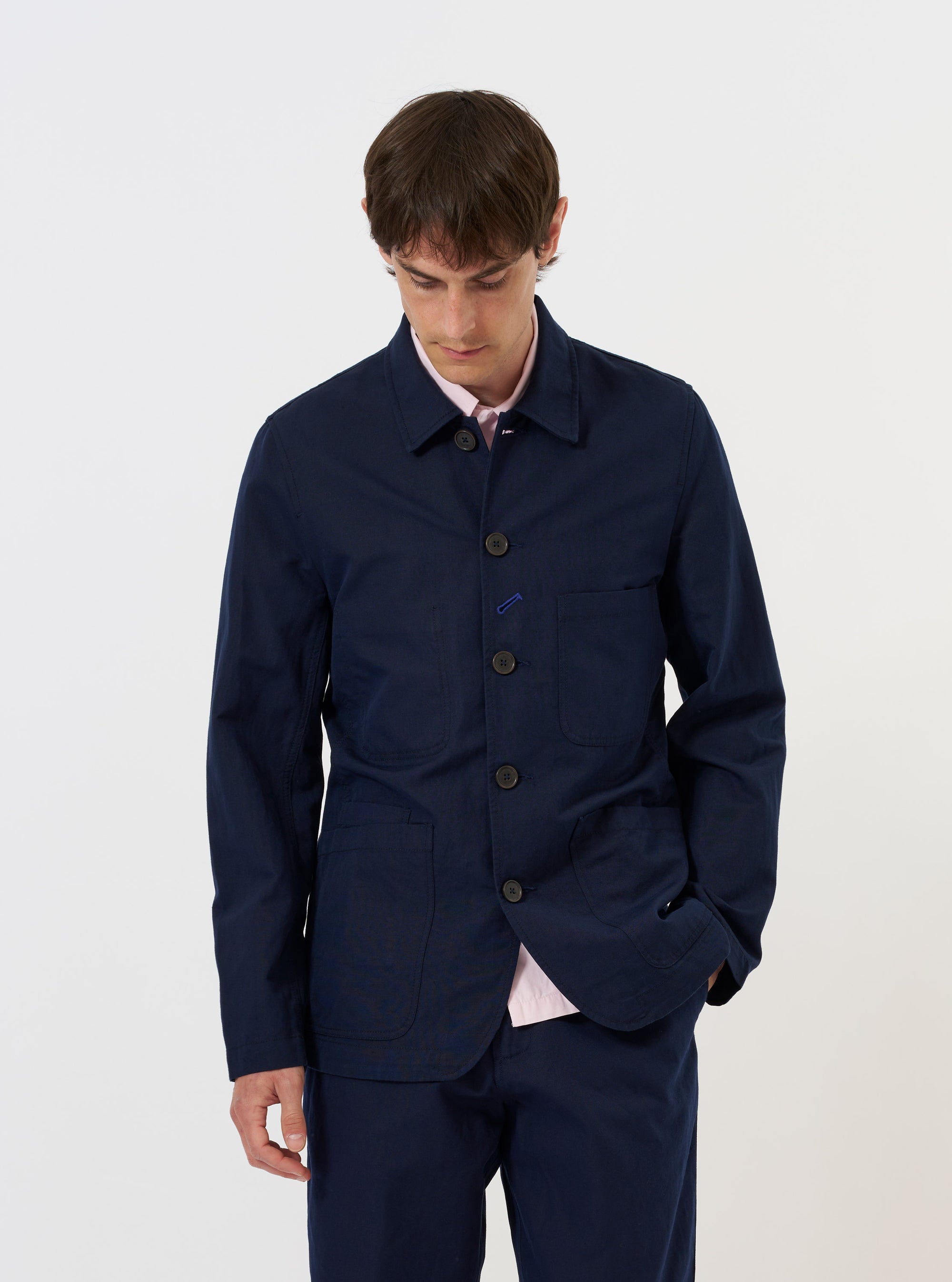 A navy blue linen slub weave Bakers Jacket is shown laid flat against a plain white background. The jacket features a five-button front, three front patch pockets, and a classic pointed collar. The textured slub weave of the fabric is visible.