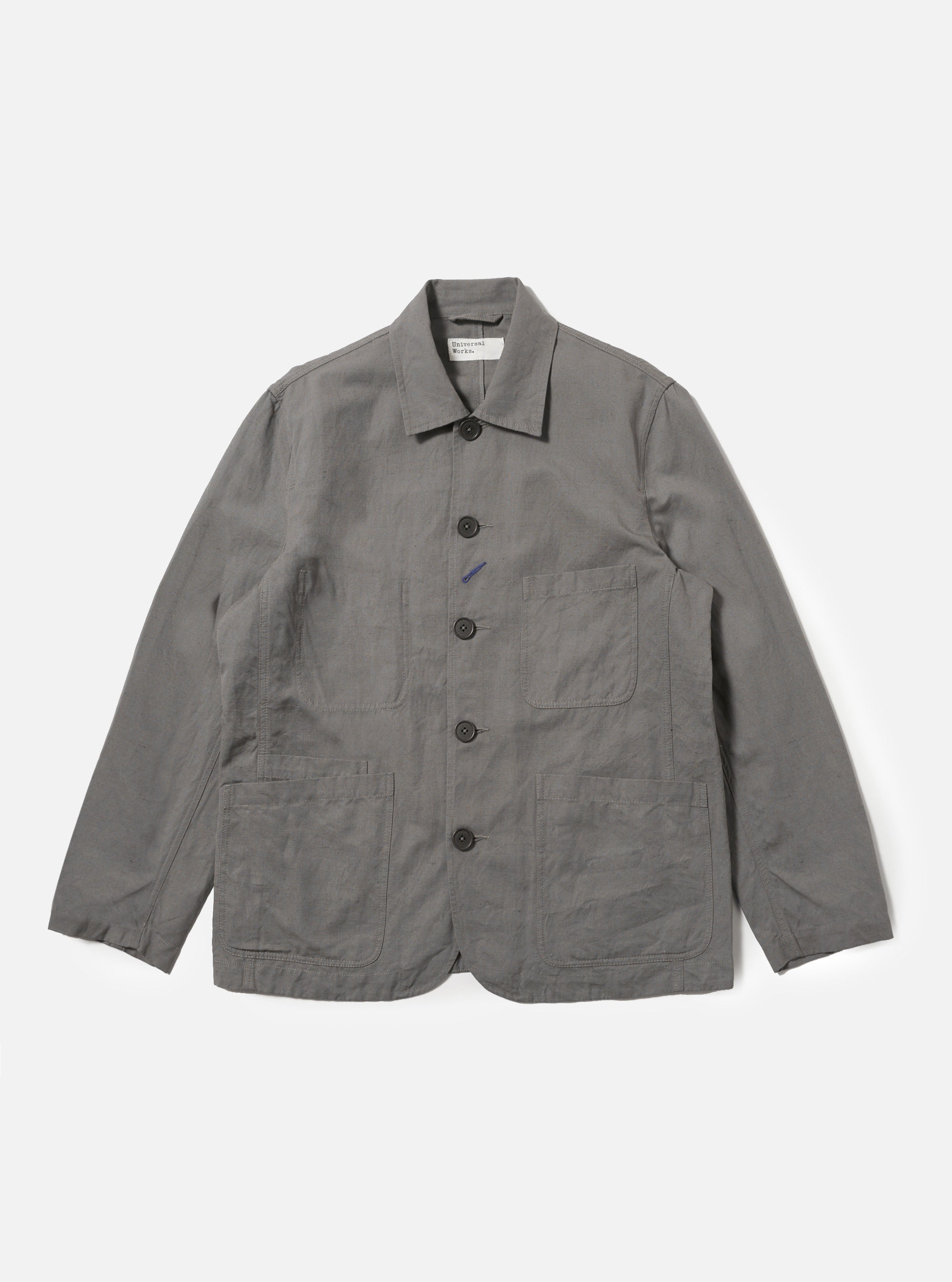 The Mid Grey Linen Slub Weave Bakers Jacket is shown laid flat against a plain white background. The garment features a five-button front, a classic pointed collar, and four front patch pockets including one with a buttoned flap. The mid-grey fabric displays a distinct slubbed texture.