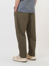 A pair of Olive Linen Slub Weave Dizzy Trousers is shown from the back, laid flat against a solid white background. The image highlights the wide, loose fit of the legs and the two rear patch pockets with buttoned flaps.