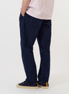A model is wearing the Navy Linen Slub Weave Dizzy Trouser against a plain white background. The image shows the trousers from the waist down, highlighting the loose, wide-leg fit and the textured slub weave of the navy linen fabric. One hand is partially visible in a side pocket.