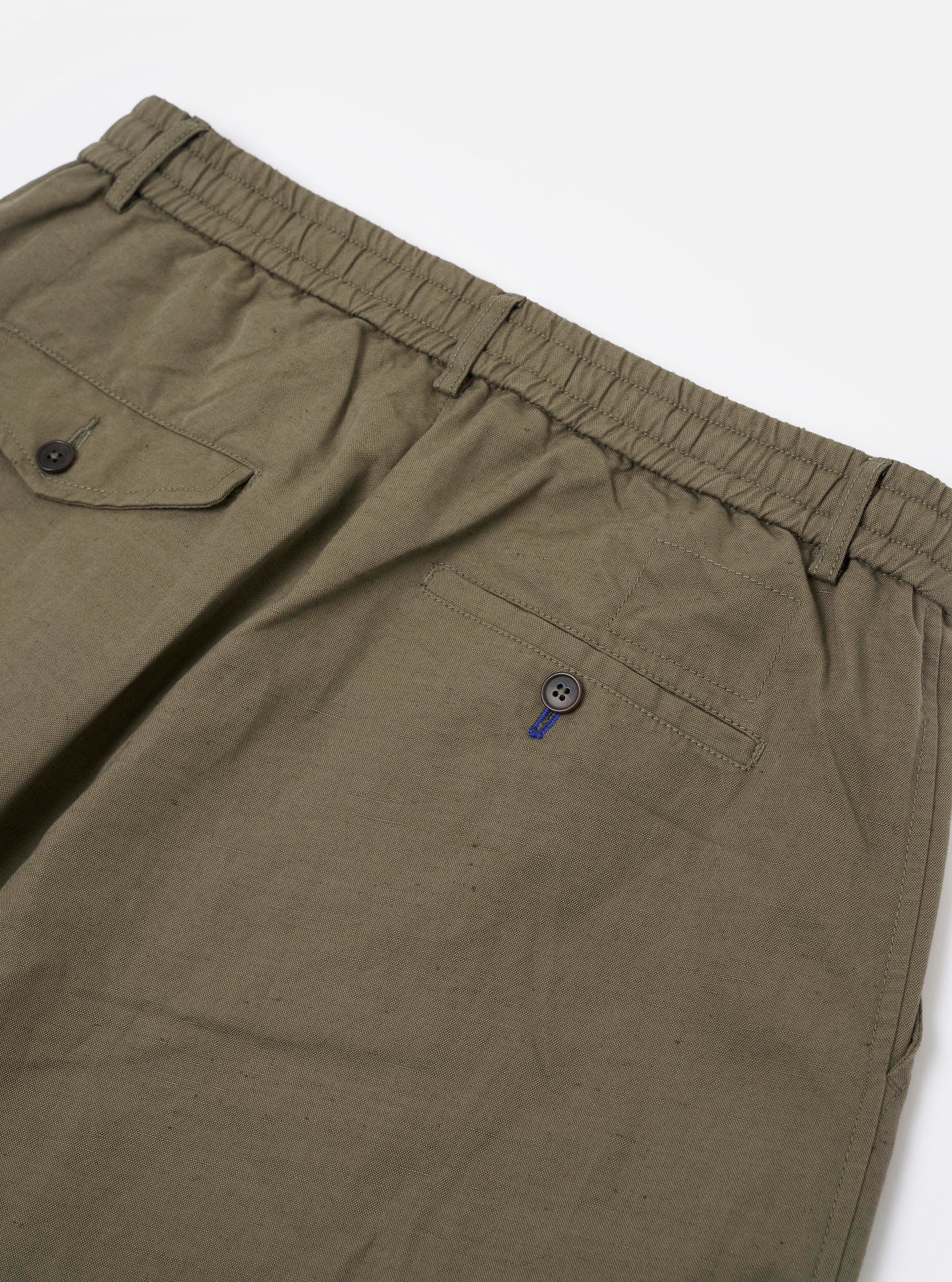 A pair of olive green linen slub weave Oxford pants is shown from the back, laid flat against a plain white background. The image highlights the elasticated waistband and two rear pockets, one with a buttoned flap and one jetted, showcasing the textured slub fabric.