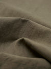 A detailed close-up fabric swatch of the Olive Linen Slub Weave Oxford Pant, highlighting the olive green color and the distinct, textured slub weave of the fabric. The material is shown against a neutral background.