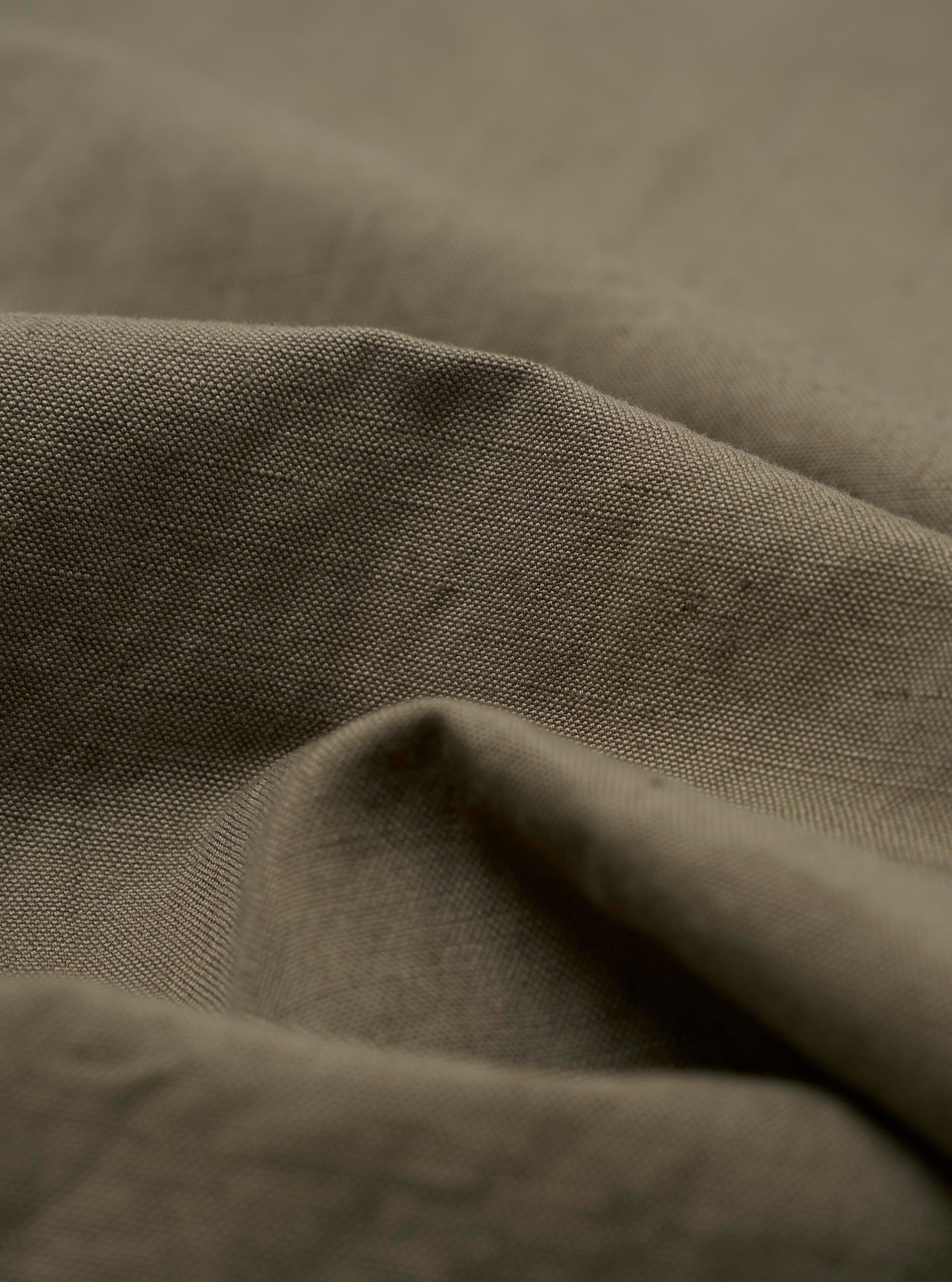 A detailed close-up fabric swatch of the Olive Linen Slub Weave Oxford Pant, highlighting the olive green color and the distinct, textured slub weave of the fabric. The material is shown against a neutral background.