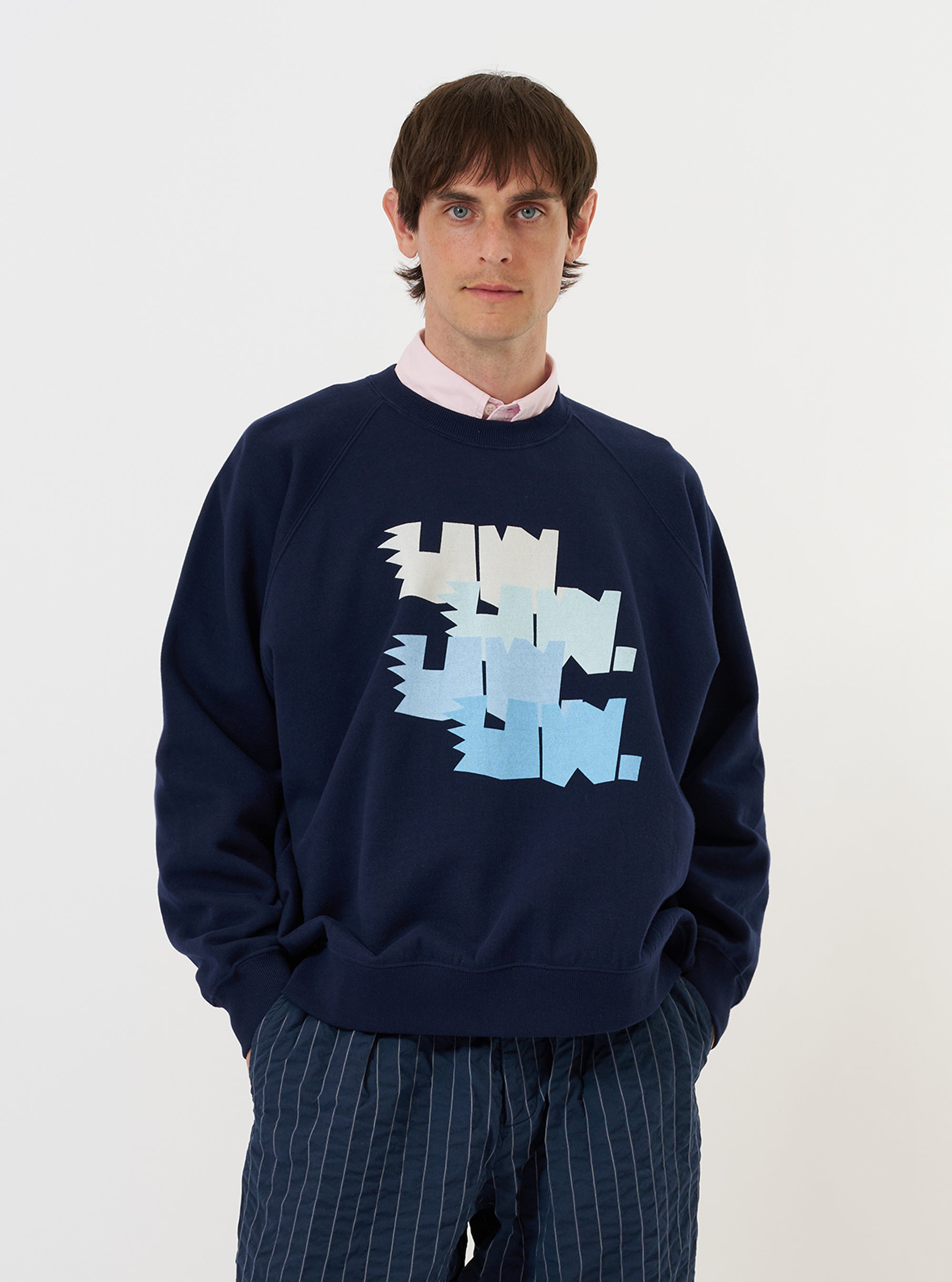 A model is wearing the Navy Brush Back Sweat FM Raglan Sweatshirt against a plain white background. The image features a front view of the navy blue sweatshirt, highlighting the raglan sleeve construction, a classic crew neckline, and ribbed detailing at the cuffs and hem.
