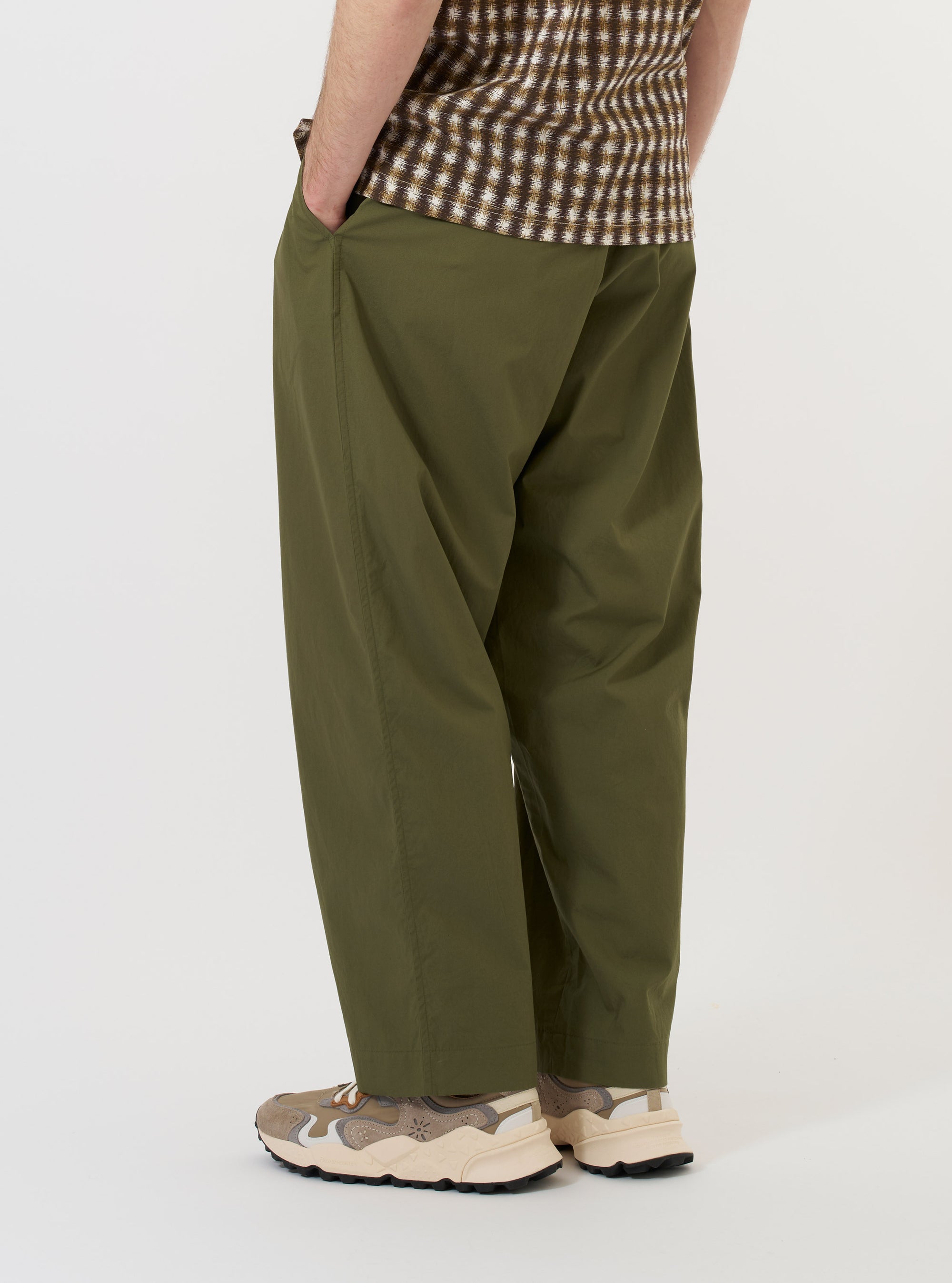 The Olive Broadcloth Oxford Pant is displayed flat against a plain white background. The image focuses on the rear of the trousers, highlighting the elasticated waistband with belt loops and two rear pockets: one a buttoned flap pocket and the other a jetted buttoned pocket. The wide, loose leg silhouette is clearly visible.
