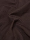 A close-up fabric swatch of the brown cotton twill material used for the Dizzy Trouser. The image captures the detailed diagonal weave and texture of the fabric.