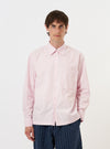 A model is wearing the Pale Pink Broadcloth Lucky Shirt against a plain white background. The shirt features a soft pink color, a relaxed fit, a pointed collar, and a full button-down front. The image captures the upper half of the model, highlighting the smooth texture of the cotton broadcloth fabric.