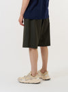 A model is wearing the Olive Marl Tropical Suiting Vacation Short against a plain white background. The olive green, knee-length shorts feature a relaxed fit and a drawstring waistband, and are shown from the back to highlight the simple, clean design and the texture of the tropical suiting fabric.