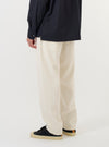 A model is wearing the Ecru Slub Drill Dizzy Trouser against a plain white background. The image captures the trousers from the waist down, showcasing the loose, wide-leg fit and the textured ecru cotton slub drill fabric. The model is standing and is also wearing dark footwear.