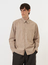 A model is wearing the Brown/White Cotton Stripe Square Pocket Shirt against a plain white background. The long-sleeved shirt features a vertical brown and white stripe pattern, a classic pointed collar, and a large, prominent square chest pocket on the left side. The model is wearing the shirt untucked, showcasing its loose fit and slightly curved hem.