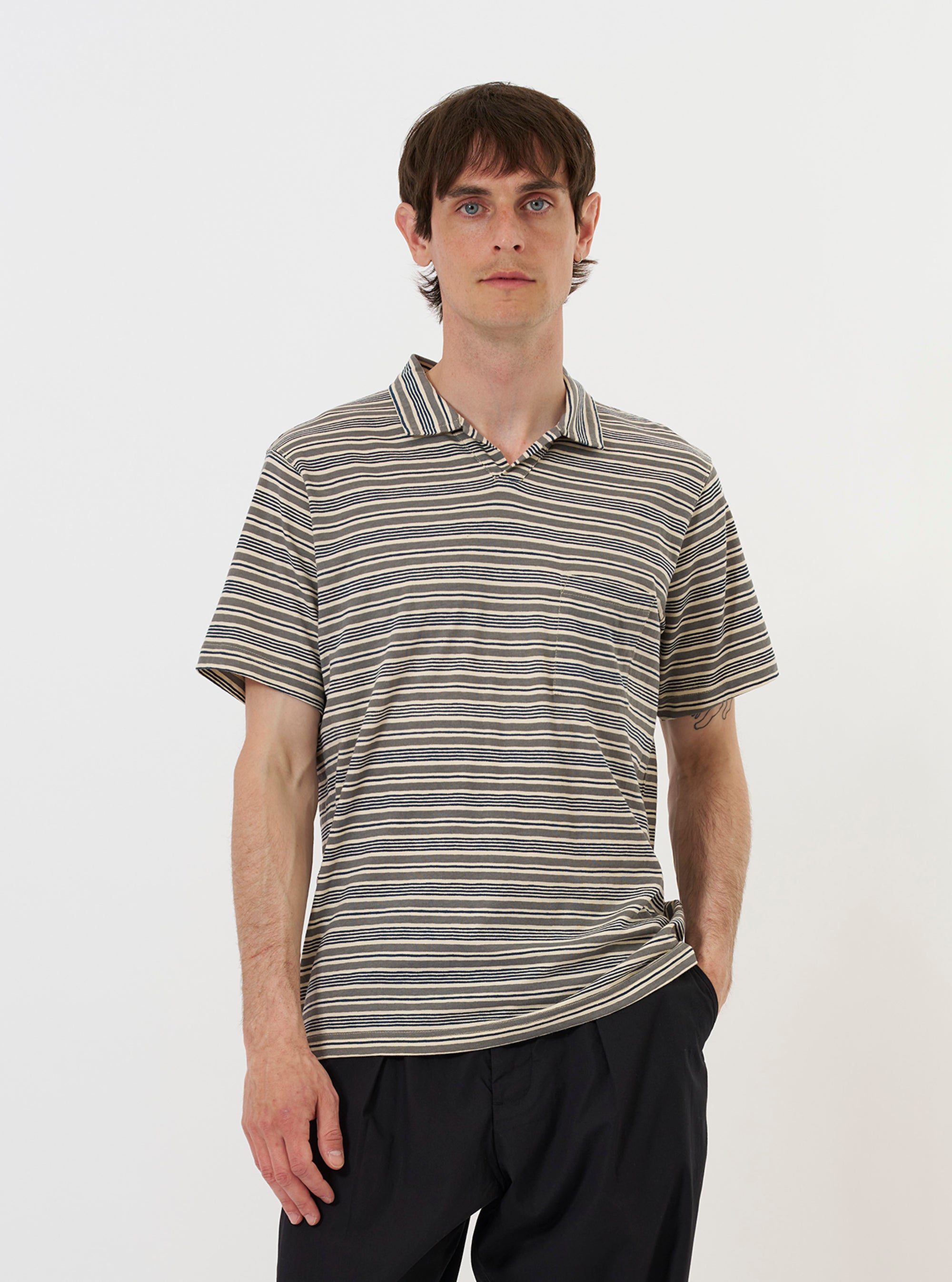 A model is wearing the Grey OS Stripe Jersey Vacation Polo against a plain white background. The short-sleeved polo features a relaxed open neck with a short front placket, a single patch chest pocket, and horizontal grey stripes. The model is shown from the waist up, and the garment is styled in a casual, open manner. No mannequin is present in the image.