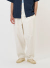 A model is wearing the Ecru Slub Drill Dutch Pant against a plain white background. The image shows the model from the waist down, highlighting the loose, wide-leg fit of the ecru-colored trousers, which feature large fatigue-style front patch pockets and a visible button fly. The model is standing straight and is also wearing navy blue shoes.