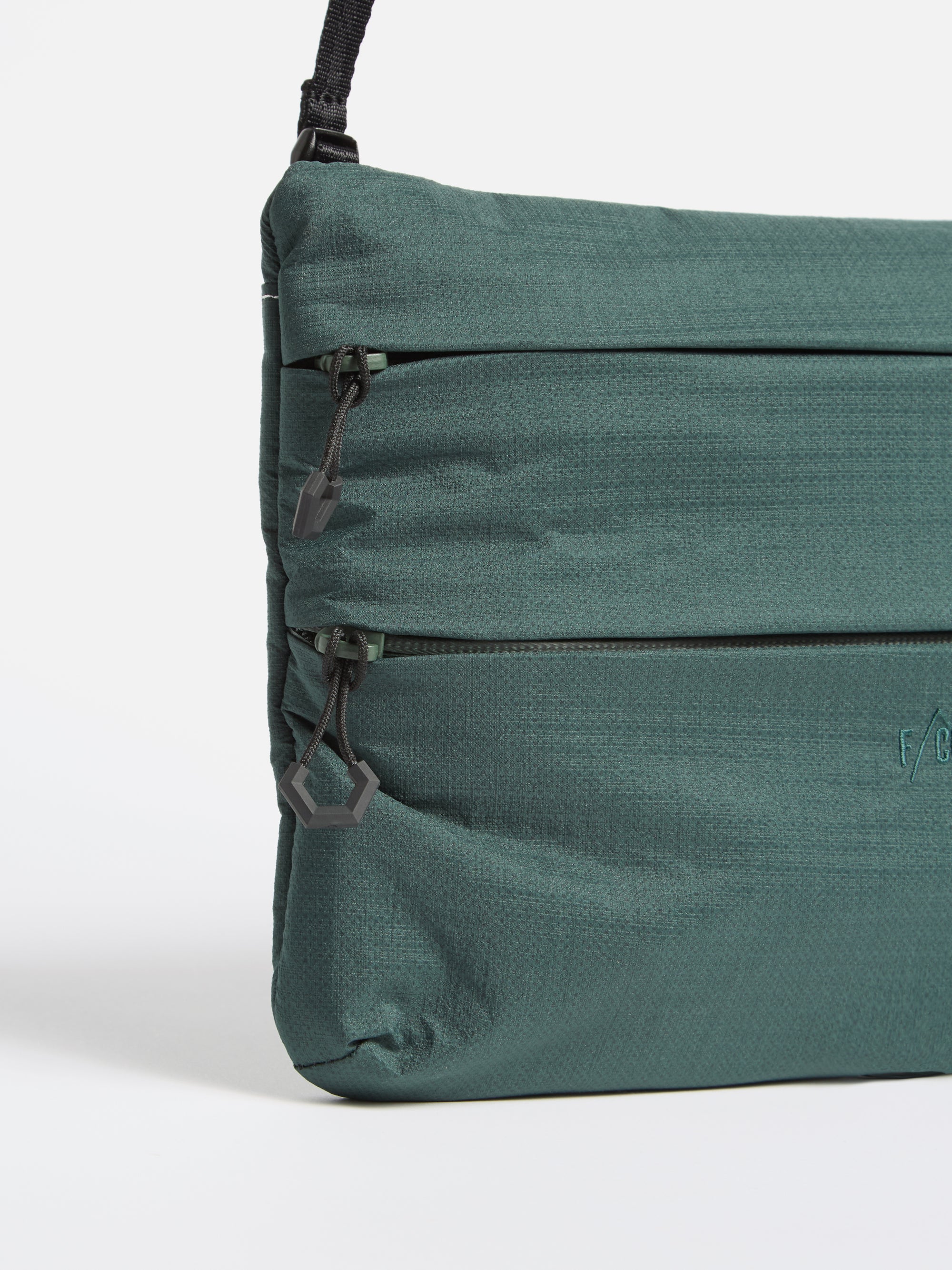 Close-up of the F/CE.® Green Nylon 2.5 Layer Sacoche on a white background. The bag features a textured green nylon material, black zippers, and a black adjustable strap.