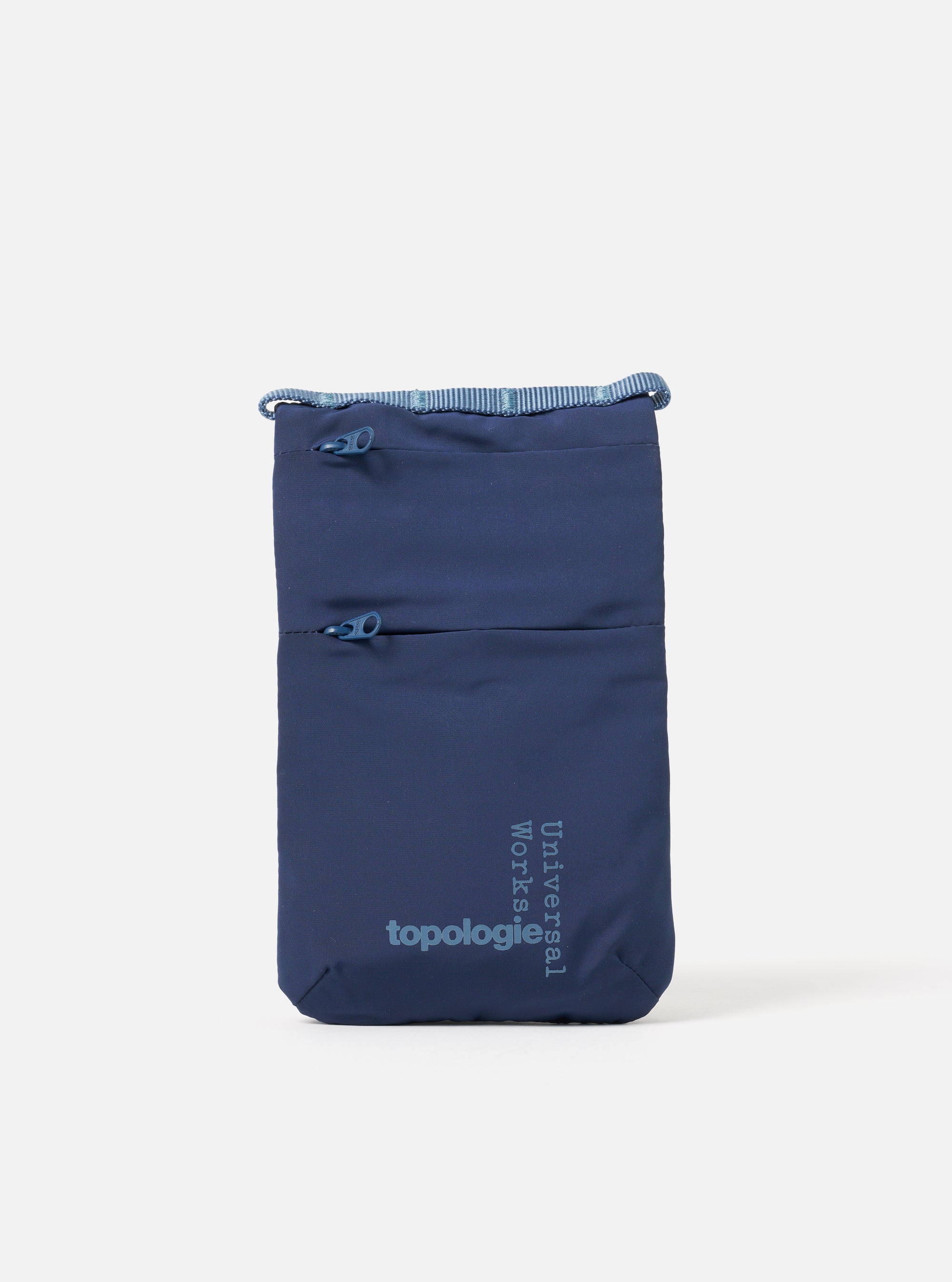 The Topologie x Universal Works Insignia Blue UW Tech Phone Sacoche on a white background. The blue bag has two zipped pockets and logos for both brands.