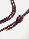 Close-up of the Topologie x Universal Works Olive Hitch UW Rope 8mm Rope Strap on a white background. The rope is a mix of navy, red, and beige, with a knot and gold metal detail.