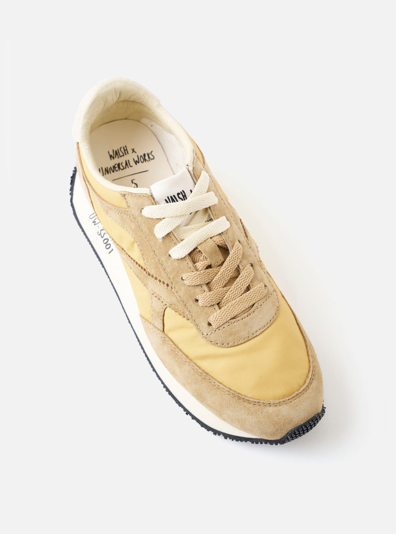 An angled front product shot of the Walsh x Universal Works Tornado in Beige Leather/Canvas on a white background, showcasing the rounded toe box, beige lace-up closure, and textured paneling.