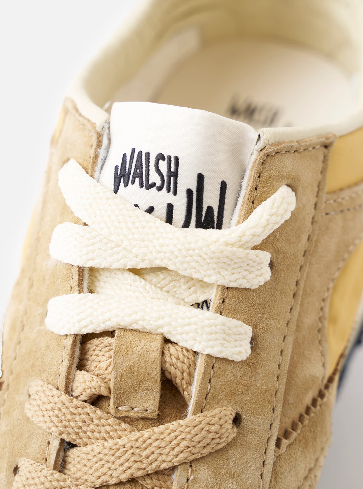A pair shot showing both left and right shoes of the Walsh x Universal Works Tornado in Beige Leather/Canvas side-by-side on a plain white background, displaying the overall retro runner design.
