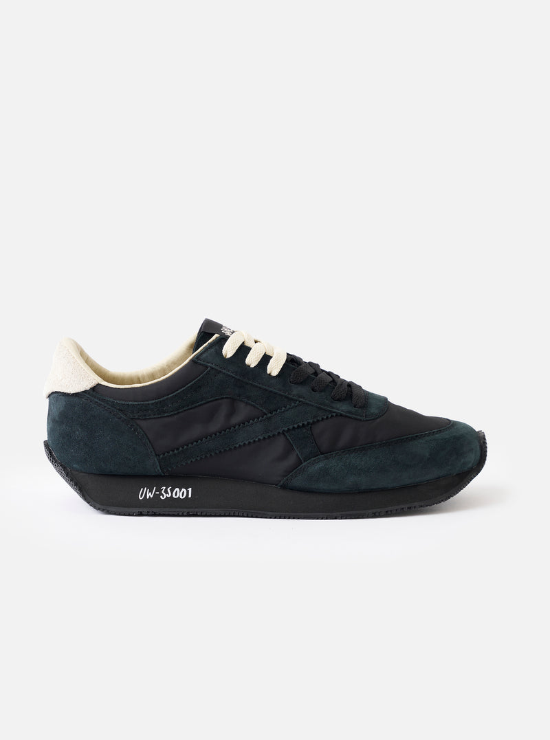 A side profile view of the Walsh x Universal Works Tornado sneaker in Black Leather/Canvas on a plain white background, highlighting the dark black suede panels, canvas upper, and contrasting white midsole.