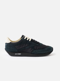 A side profile view of the Walsh x Universal Works Tornado sneaker in Black Leather/Canvas on a plain white background, highlighting the dark black suede panels, canvas upper, and contrasting white midsole.