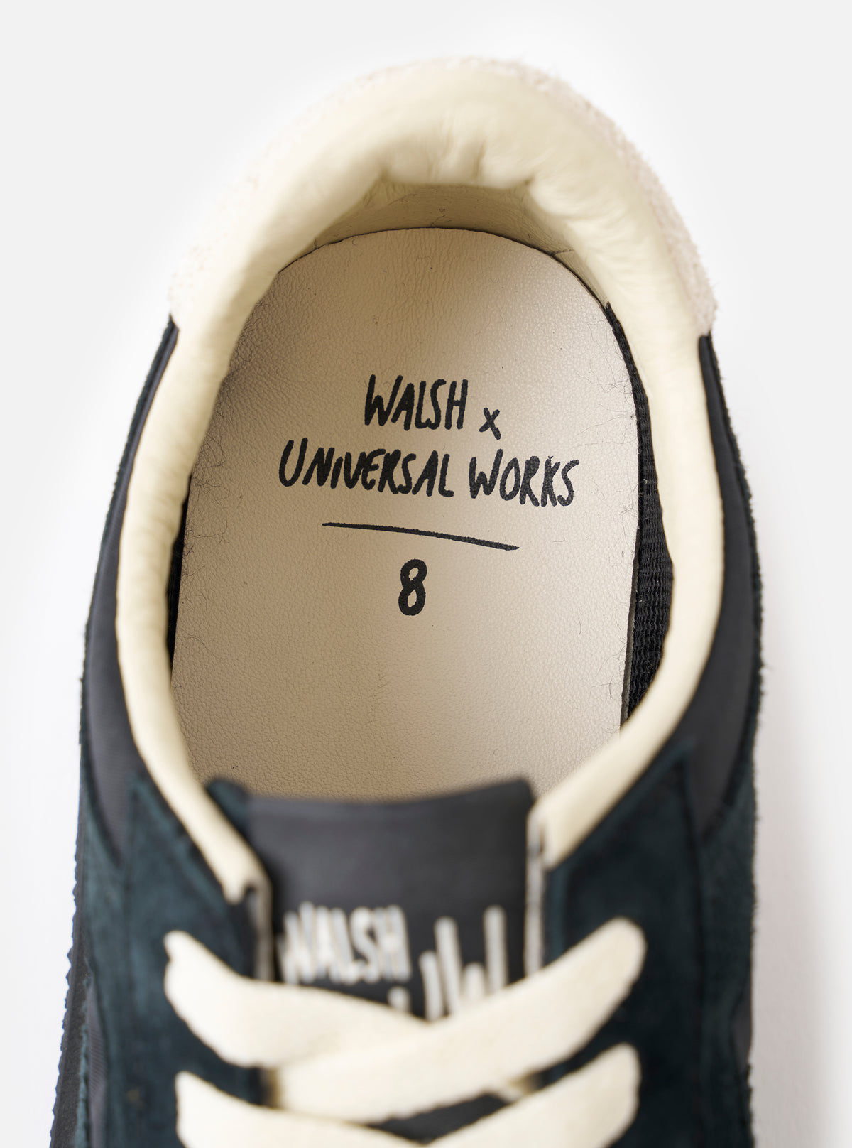 A bottom view showing the rubber tread sole of the Walsh x Universal Works Tornado in Black Leather/Canvas against a white background, emphasizing the deep traction pattern and sole grip.