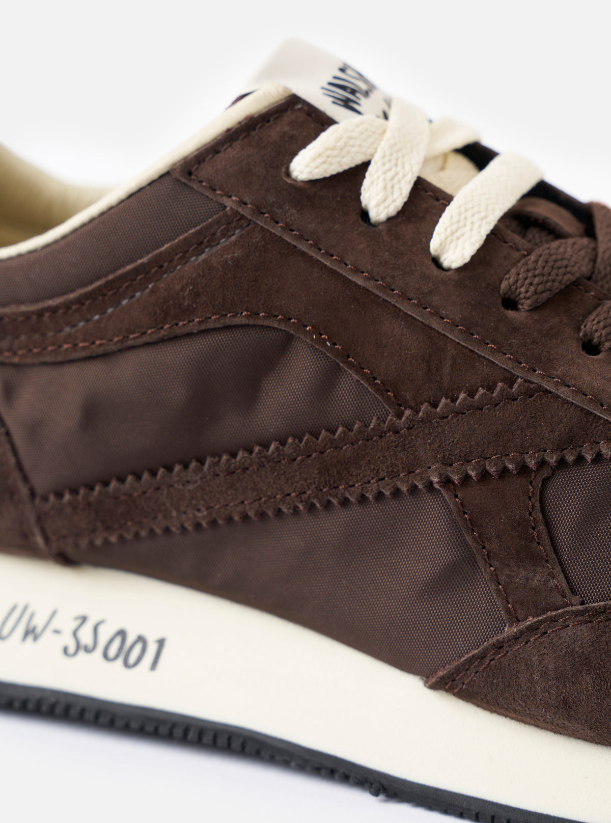 A top-down overhead view of the Walsh x Universal Works Tornado sneakers in brown leather and canvas on a plain white background, highlighting the brown laces, branded insoles, and streamlined toe box structure.