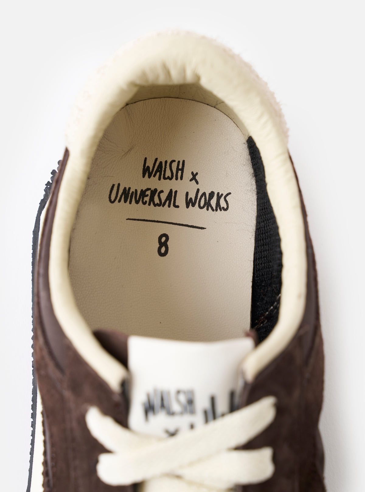 A detailed close-up shot of the heel section of the Walsh x Universal Works Tornado in Brown Leather/Canvas against a plain white background, highlighting the contrast stitching and padded collar.