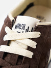 A detailed view of the black rubber outsole tread on the Walsh x Universal Works Tornado in Brown Leather/Canvas displayed against a stark white background, showing grip patterns and durability.