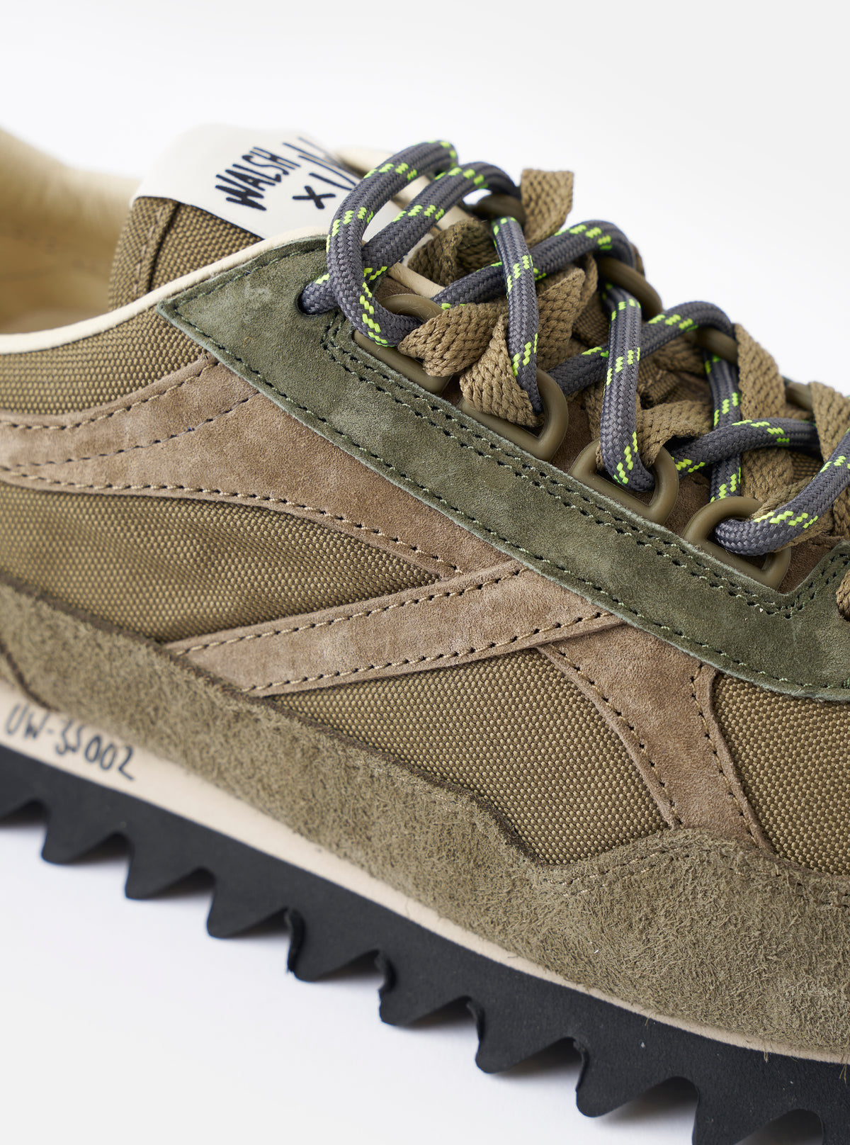 A top-down overhead shot of the Walsh x Universal Works Ensign in Green Leather/Canvas sneaker set against a plain white background, illustrating the lace arrangement, branded inner sockliner, and classic runner shape.