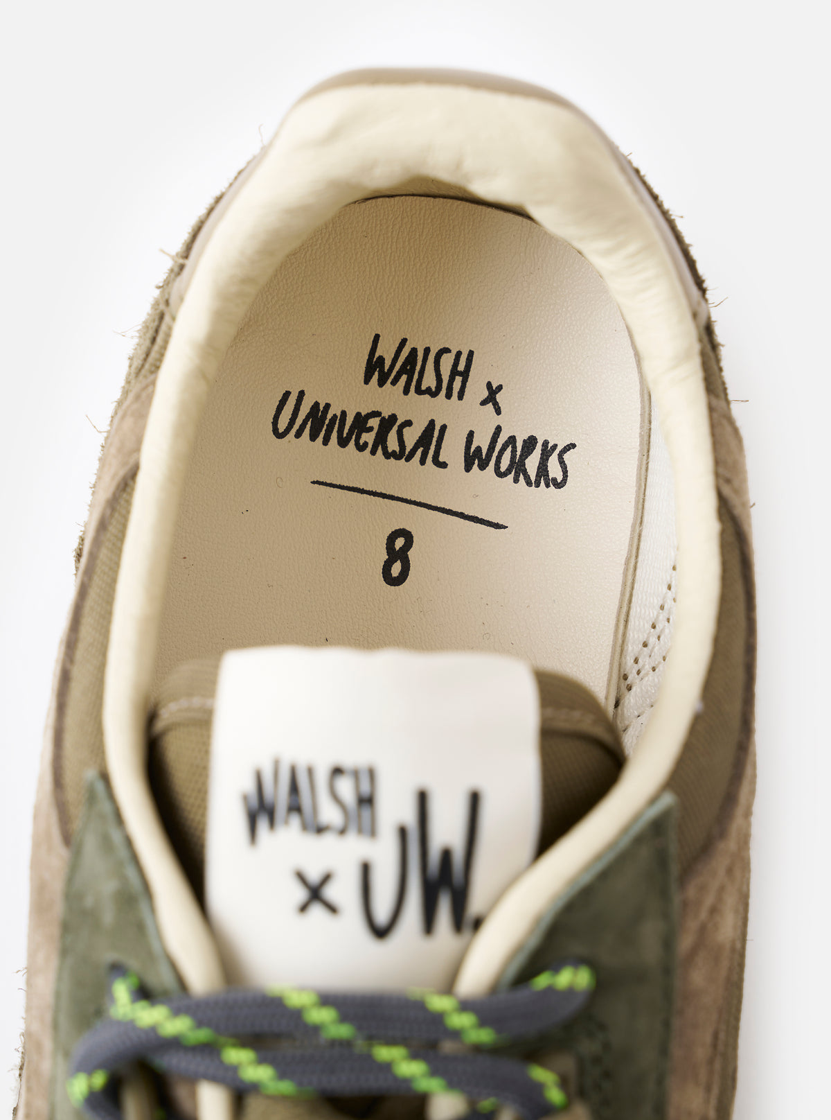 An angled view of the tread pattern on the bottom sole of the Walsh x Universal Works Ensign in Green Leather/Canvas sneaker, captured against a neutral white background to show the multi-directional traction design.