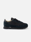 A side profile view of the Walsh x Universal Works Ensign in Black Leather/Canvas on a white background, highlighting the sleek black upper, layered leather panels, and off-white cushioned midsole.