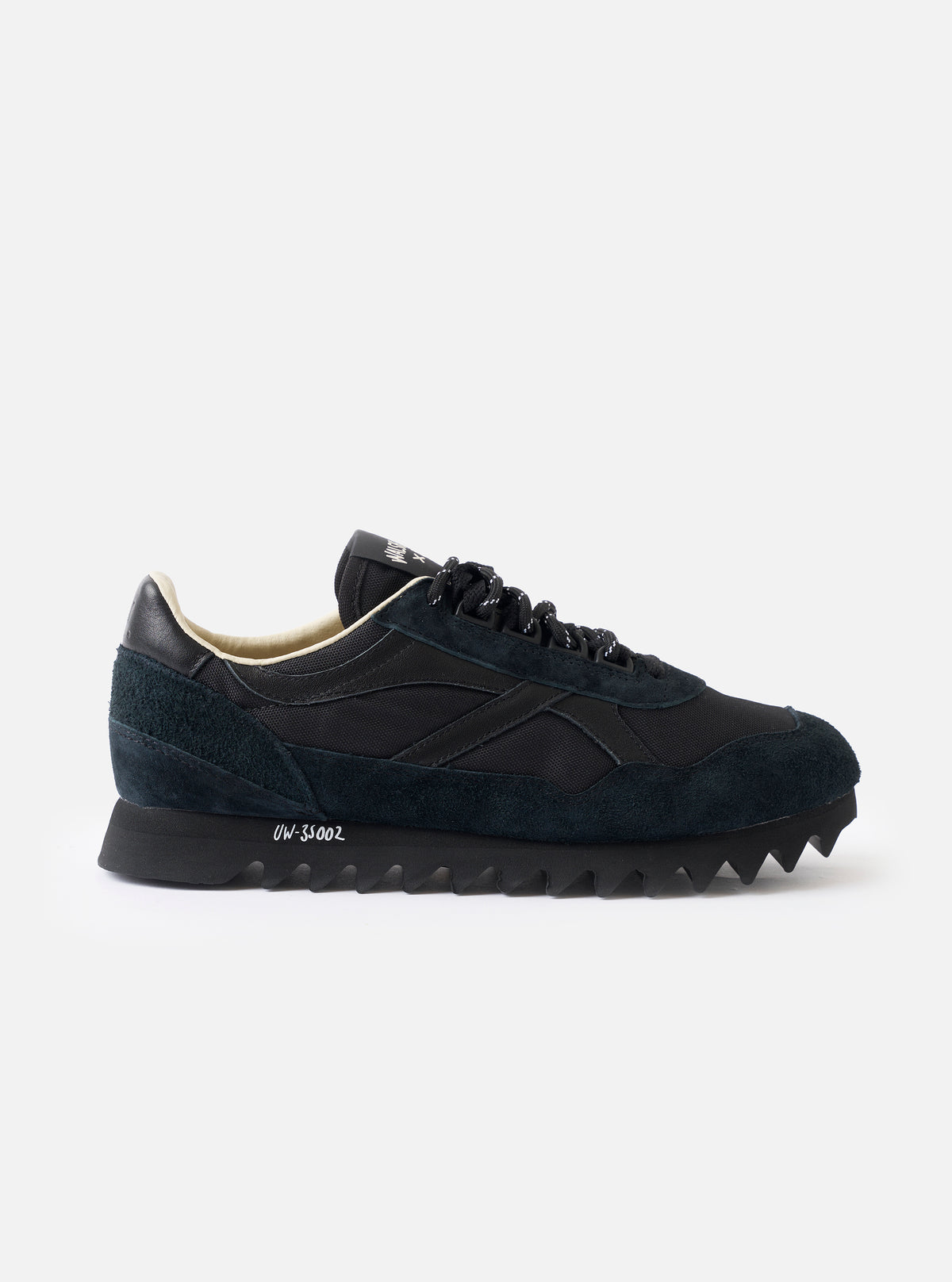 A side profile view of the Walsh x Universal Works Ensign in Black Leather/Canvas on a white background, highlighting the sleek black upper, layered leather panels, and off-white cushioned midsole.