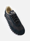 An angled three-quarter shot of a pair of Walsh x Universal Works Ensign in Black Leather/Canvas sneakers on a white background, showing the black laces, textured canvas, and solid structure.