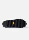 A clear view of the black textured rubber outsole of the Walsh x Universal Works Ensign in Black Leather/Canvas placed against a white background, demonstrating the grippy tread construction.