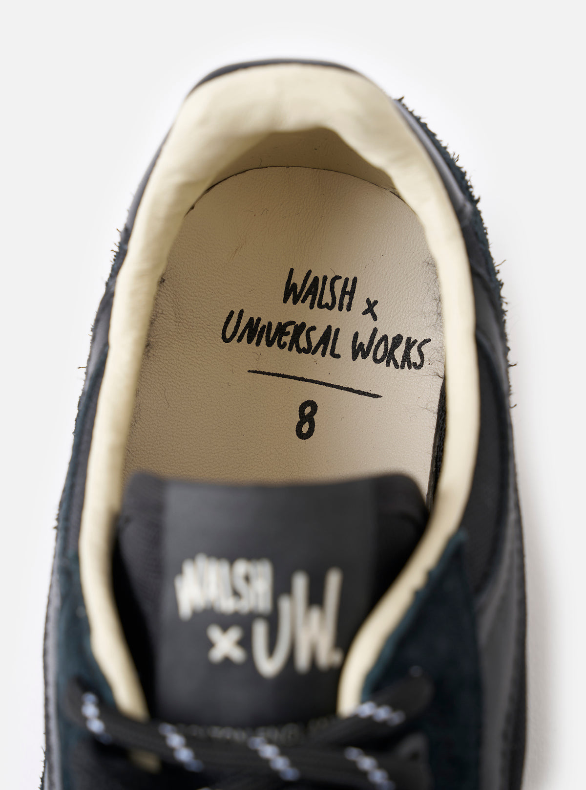 An angled detail shot of the side upper of the Walsh x Universal Works Ensign in Black Leather/Canvas on a plain white background, showcasing the mixed material leather and canvas paneling.