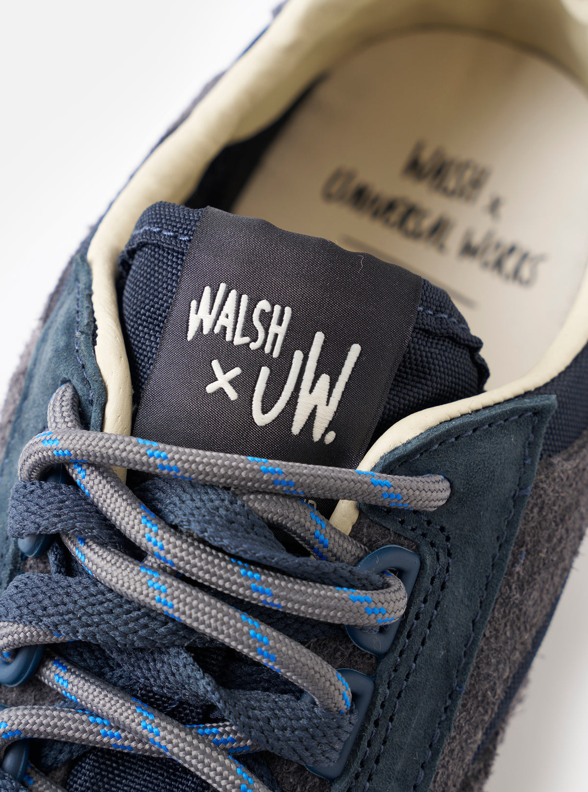 An angled view of the sole of the Walsh x Universal Works Ensign in Navy Leather/Canvas sneaker presented against a plain white background, illustrating the deep tread pattern and rugged rubber outsole design.
