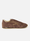 A side profile shot of the Walsh x Universal Works Cob in Brown Leather trainer isolated on a plain white background, featuring a rich brown suede upper, low-profile silhouette, and slim gum rubber sole unit.