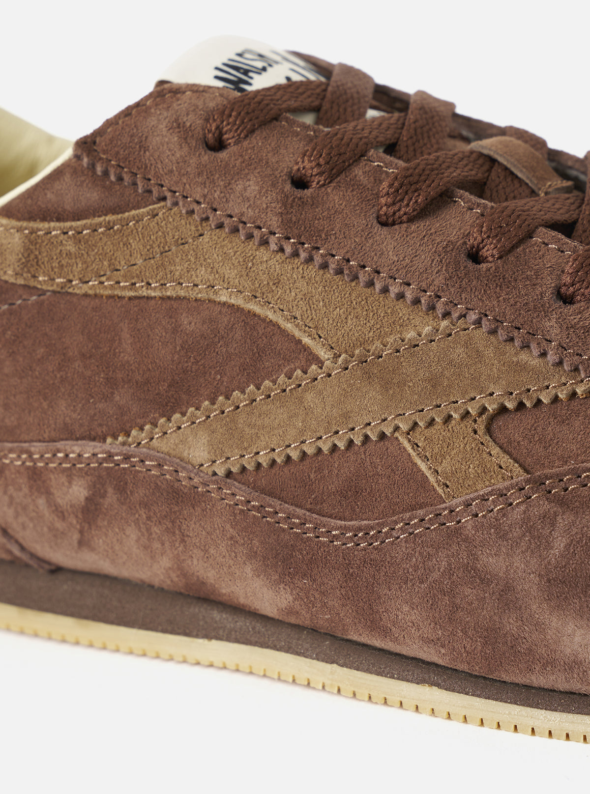 A top-down aerial view of the Walsh x Universal Works Cob in Brown Leather trainer against a plain white background, detailing the symmetry of the lace placket, soft leather lining, and minimalist internal branding.
