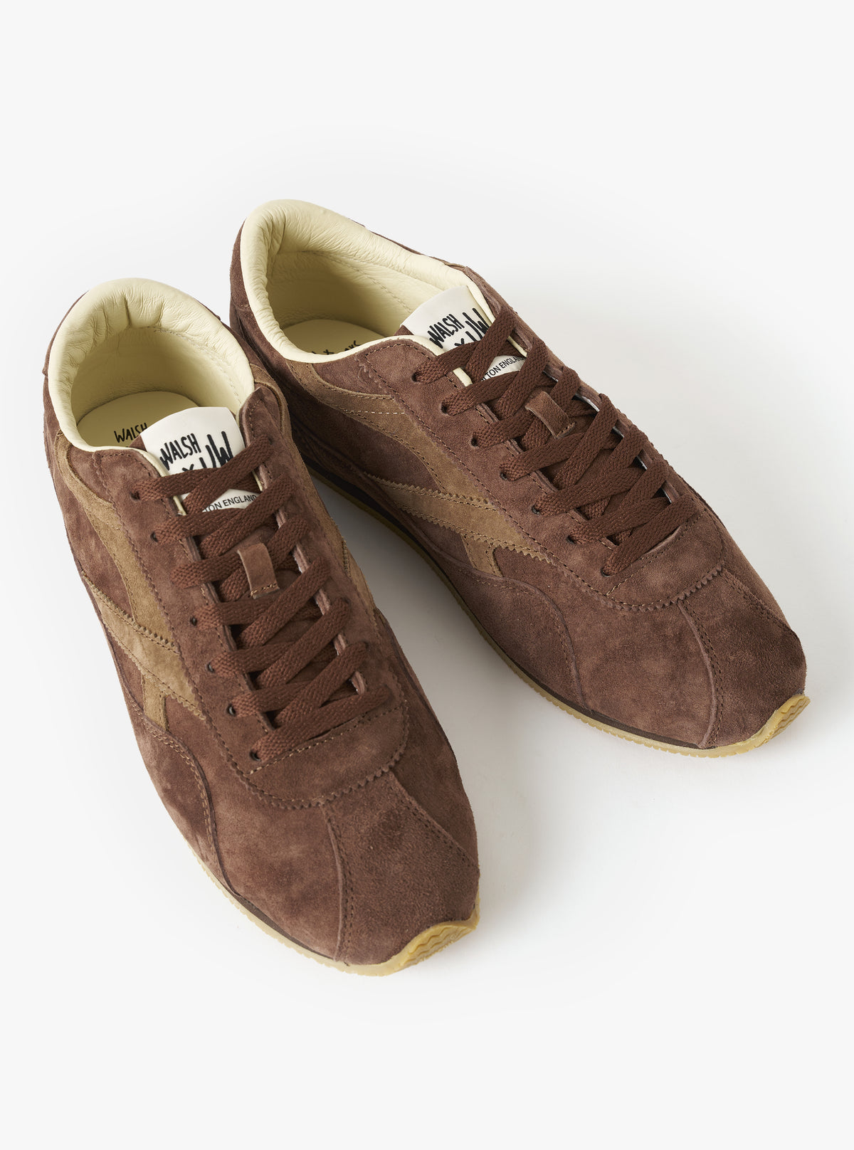 A back view of the Walsh x Universal Works Cob in Brown Leather trainer set on a clean white studio background, showcasing the soft heel overlay, low ankle cutout, and flush rubber outsole edge.