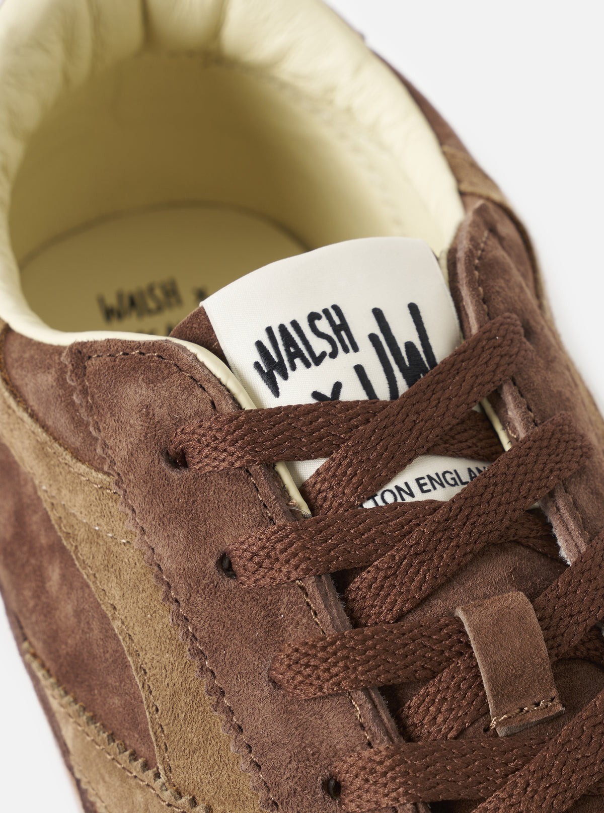 Detailed close-up view of the Walsh x Universal Works Cob in Brown Leather, showing the textured grain leather upper, subtle stitching details, and soft collar trim against a clean, off-white studio background.