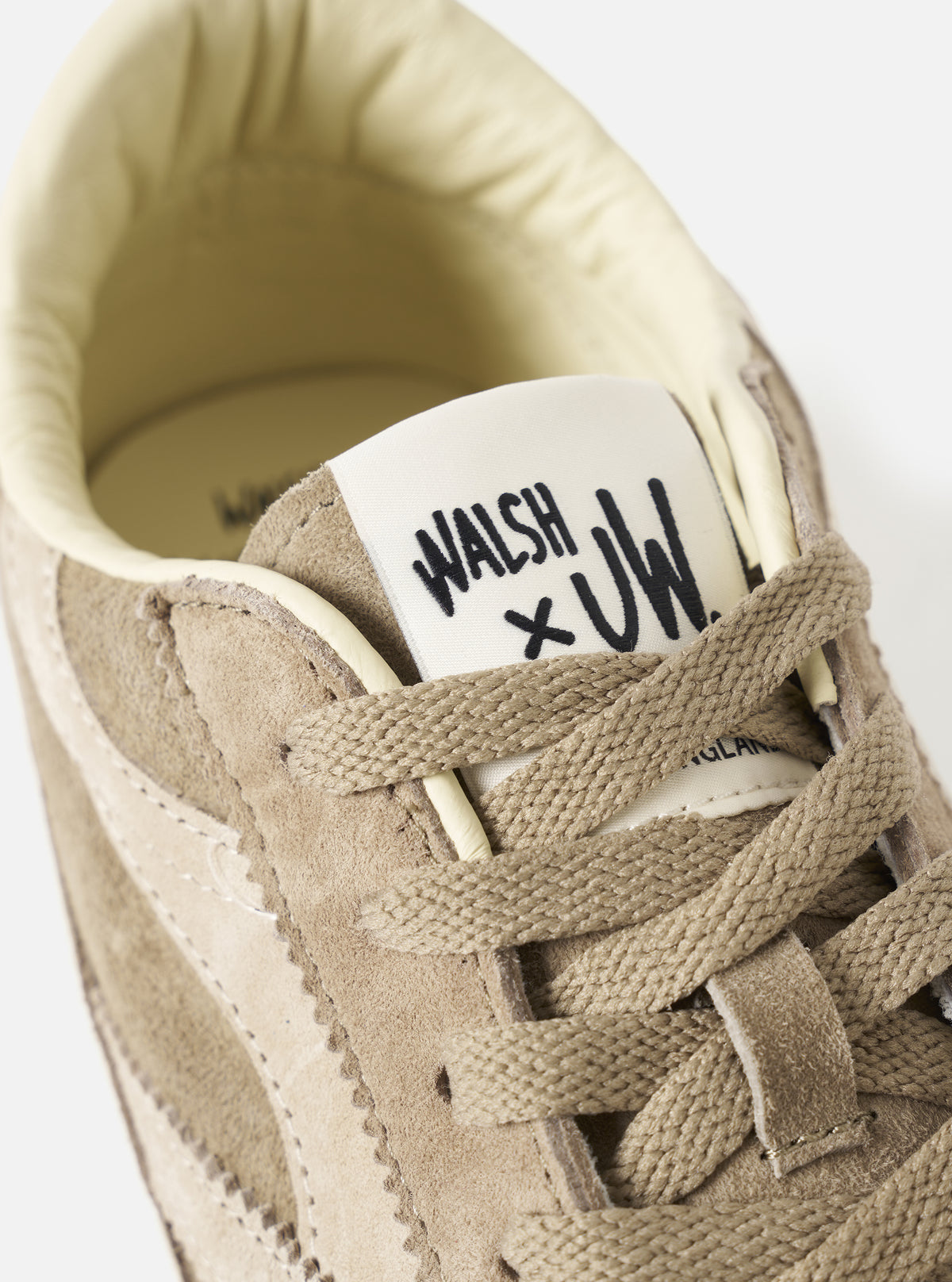 Extreme close-up detail shot of the Walsh x Universal Works Cob in Camel Leather upper on a light background, emphasizing the premium grain texture, eyelets, and tonal laces of the collaborative shoe.