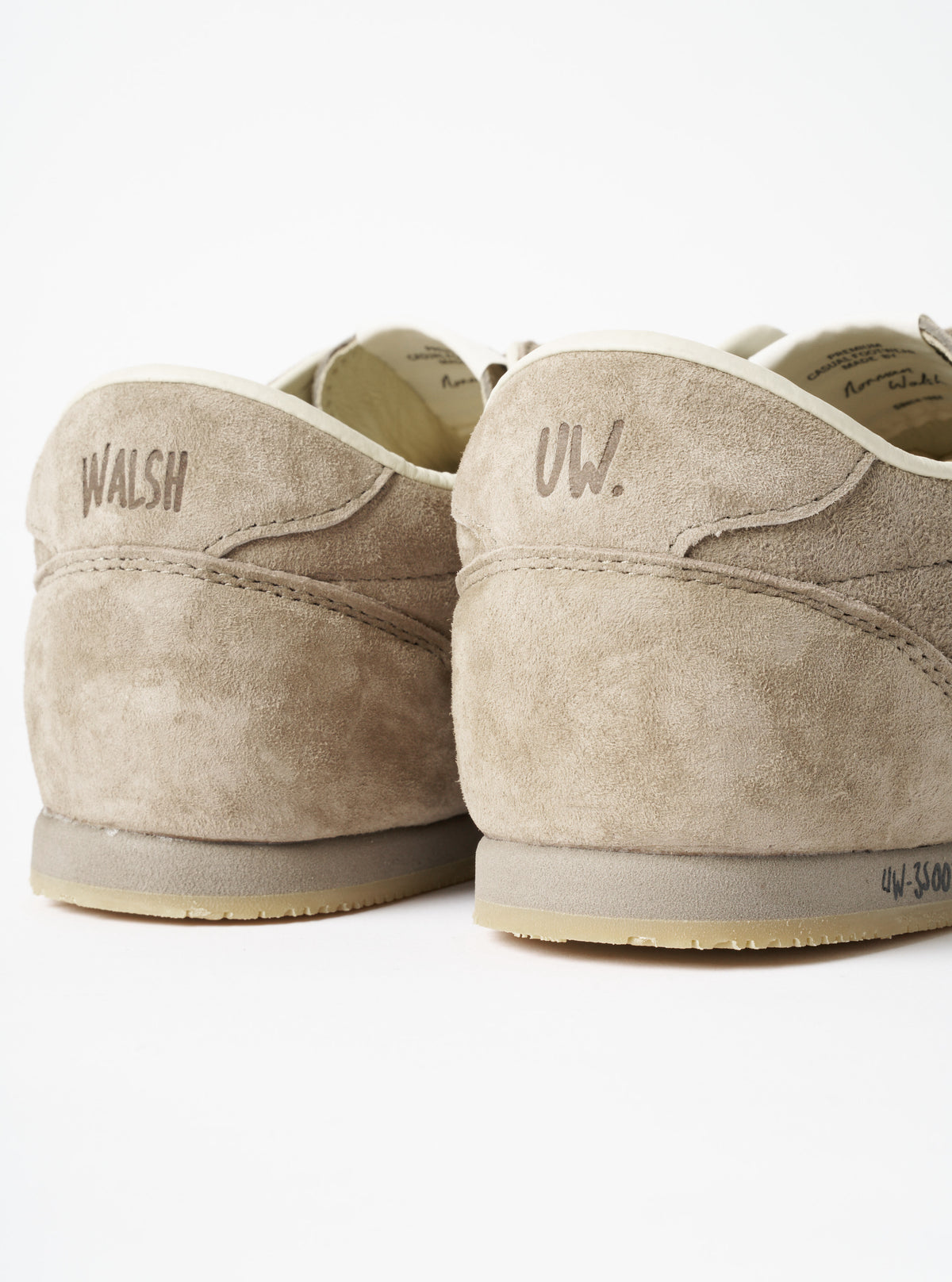 A model wearing the Walsh x Universal Works Cob in Camel Leather on foot, captured in a clean studio setting to showcase how the low-top camel leather footwear sits naturally with cuffed trousers.