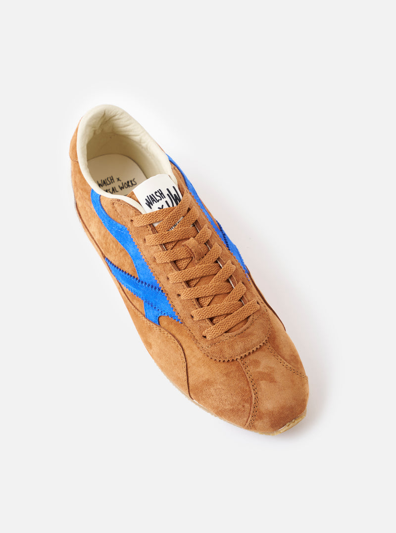 Side view studio photo of the Walsh x Universal Works Cob in Tan Leather, highlighting the contoured profile, layered paneling, lace eyelets, and durable rubber sole against a neutral studio background.
